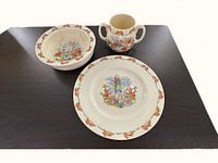 Children's dinner set pieces displayed: dinner plate, deep bowl, and two-handled cup with Bunnykins designs.