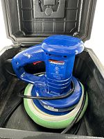 Blue Simoniz electric car polisher with attached green and white bonnet inside black carry case showing the handle and base.