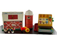 Photo showing the entire Fisher Price Family Play Farm set including barn, silo, tractor, and cash register on a black surface.