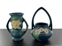 Double handled vase and basket side by side on dark surface, showing overall shape and decoration