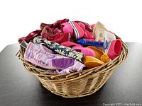 Wicker basket filled with assorted colorful doll shoes and boots in pink, red, yellow, and blue tones
