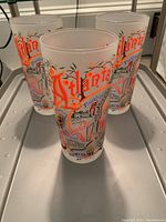 Three frosted glasses decorated with colorful Atlanta landmarks and text, arranged in triangular formation on gray surface under natural light.