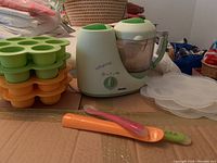 Whole lot including Babycook food maker, stackable storage keepers, lids, and spoons.