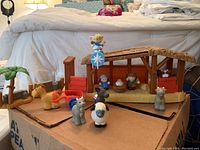 Fisher Price Little People Nativity scene set with stable, figurines of Mary, Joseph, baby Jesus, angel, and animals including camel, donkey, sheep, and cow on cardboard box base.