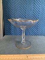 Full view of the fluted crystal candy dish showing gold trimmed scalloped edges and faceted stem