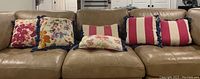 Full view of all six pillows arranged on a sofa showing variety in color and trim.