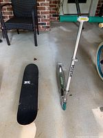 Photo showing Razor collapsible scooter and Krown skateboard side by side on concrete floor.
