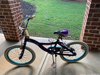 Full view of the purple and pink kids bicycle showing frame, tires, pedals, handlebar and kickstand