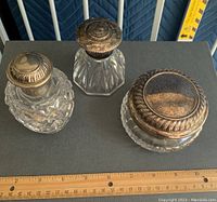 Three Waterford crystal bathroom vanity containers with sterling silver caps, displayed on a dark cloth with ruler for scale.