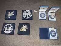 Seven assorted Wedgwood Christmas ornaments arranged on floor, each in blue display boxes or packaging.