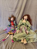 Both dolls seated against a plain backdrop, showing full body with detailed clothing and feet.