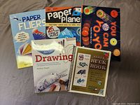 Photo of five activity books related to paper folding, yo-yo tricks, drawing, and dollar bill art, all paperback and in like-new condition
