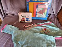 All items in lot arranged on couch: child's kimono, boxed Q Alloy Car set, paper plane making kit