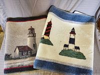 Two folded rugs with lighthouse patterns showing details of designs and colors.