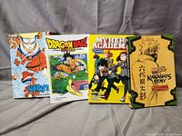 Photo of 4 manga paperback books: Naruto 3 in 1 volume, DragonBall Super, My Hero Academia School Briefs, Naruto Kakashi Story. Books are in like new condition with colorful and detailed covers.