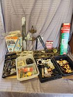 Wide view showing all miscellaneous hardware items including fill valves, door insulator strips, seals, nails, hinges, and assorted small parts arranged on a flat surface.