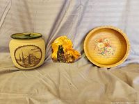 Front view of the ceramic jar with lid, rock slab, and wooden bowl displayed side by side on a fabric surface.