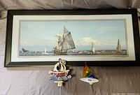 Framed panoramic photo print depicting many sailboats on the water with Mt Rainier in the background, displayed horizontally with two small sailboat nightlights in front.