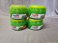 Four new and unopened green containers of Turtle Wax Super Hard Shell car wax stacked in two pairs.
