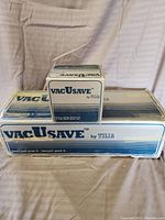 Photo of multiple sealed boxes of VacUsave vacuum sealing accessories by Tilia showing packaging and product branding.