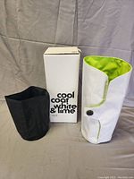 Two wine bottle coolers with box, white & lime cozy and black cozy placed on table