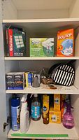 Shelf view showing SanitAire HEPA filter box, Swiffer cloths, and Bounce dryer sheets along with other cleaning supplies and bags.