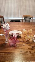 Set of blown glass flowers, vase, and decorative bowl on wooden table.