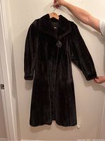 Front view of full-length dark brown mink coat on hanger