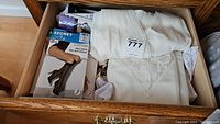 Drawer containing two white slips with lace detail and a packet of knee highs and other hosiery.