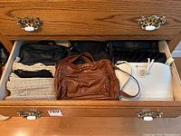 Drawer containing six handbags of varying styles and colors as the main overview image of the lot.