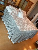 Full bed showing floral comforter, grey star-patterned bedskirt, and pillows on top