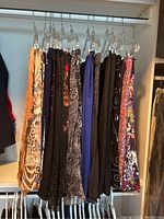 Hanging skirts and pants on clear plastic hangers on rod, variety of colors and patterns visible, mostly size small to medium.