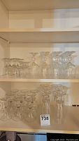 Shelves displaying several clear glass stemware pieces including sherry and wine glasses in groups.