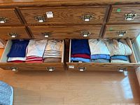 Drawers opened showing folded women’s sweaters and tops in various colors and styles
