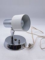 Front view of the desk lamp showing the chrome base with switch and white adjustable cylindrical lamp shade.