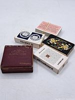 Lot consisting of four different groups of playing cards including a maroon Waddington's Cro-Quor box, black floral box, Olinebani maze design box, and loose red-backed cards.