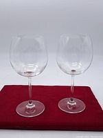 Pair of clear wine glasses on red cloth background.