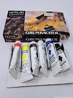 Box and tubes of acrylic paints laid on white surface showing condition and branding.