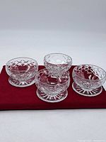 Five crystal bowls displayed on red cloth, showing diamond cut design and pedestal bases.