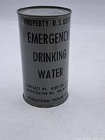Front perspective view of gray metal cylindrical tin can with black text