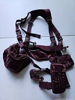 Full view of the maroon harness belt laid out showing multiple adjustable straps and attached pouches.