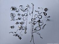 Photo showing assorted vintage sterling silver jewelry including rings, pendants, chains, and separated earrings mostly for scrap.