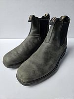 Front and top angled view of greyish-black Blundstone Chelsea boots with elastic sides and branded pull tabs, showing matte distressed finish.