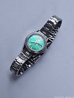 Full view of the ladies Orient automatic watch showing turquoise dial and metal band, placed flat.