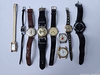 Full lot view of 9 various vintage wristwatches with leather and metal bands, different dial styles and brands.