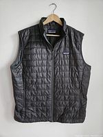Front view of dark gray men's Patagonia vest with full zipper and two side pockets visible.