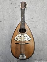 Front view of the bowl back mandolin showing soundboard, decorative inlay, fingerboard with dot markers, and strings.