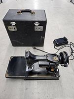 Machine, foot pedal and carrying case arranged on floor