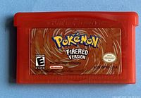 Front view of the red translucent cartridge with the Pokémon FireRed Version label clearly visible including rating and official seal.