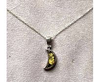 Close-up of the crescent moon pendant with yellow amber framed in silver, showing details of the amber inclusions and silver crafting.